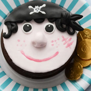 Un biscuit dACcorAC ressemblant A? un pirate avec une tAate de mort sur son chapeau, un sourire rose et des piA?ces d'or A? cA?tAC.