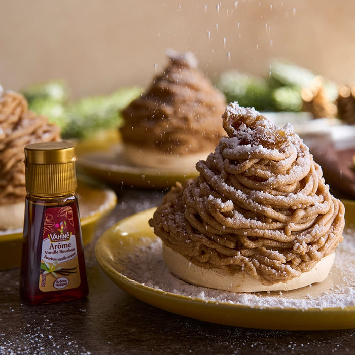 Un dessert Mont Blanc saupoudrAC de sucre glace est posAC sur une assiette jaune A? cA?tAC d'une bouteille de CrA?me de Marrons Clement Faugier.