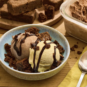 Un bol de crA?me glacACe avec des morceaux de brownie et de sauce au chocolat est prACsentAC A? cA?tAC d'un rACcipient de crA?me glacACe et d'une assiette de brownies.