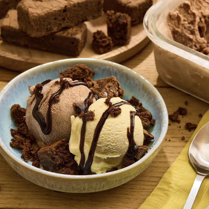 Un bol de crA?me glacACe avec des morceaux de brownie et de sauce au chocolat est prACsentAC A? cA?tAC d'un rACcipient de crA?me glacACe et d'une assiette de brownies.