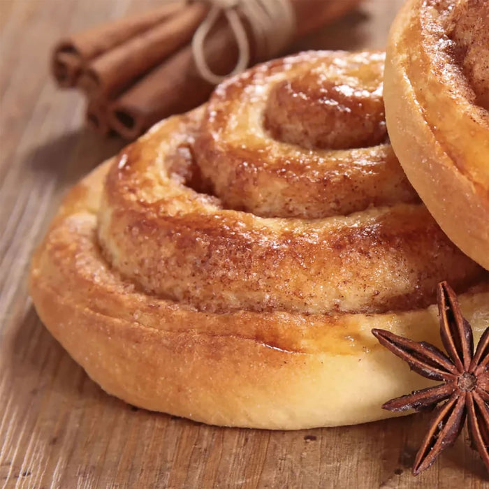 Une dAClicieuse brioche A? la cannelle avec un glaA?age brillant est posACe A? cA?tAC de bActons de cannelle et d'anis ACtoilAC, ACvoquant une sensation chaleureuse et rACconfortante.