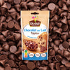 Un sachet de pépites de chocolat au lait Vahiné est présenté sur un fond de pépites de chocolat éparpillées.