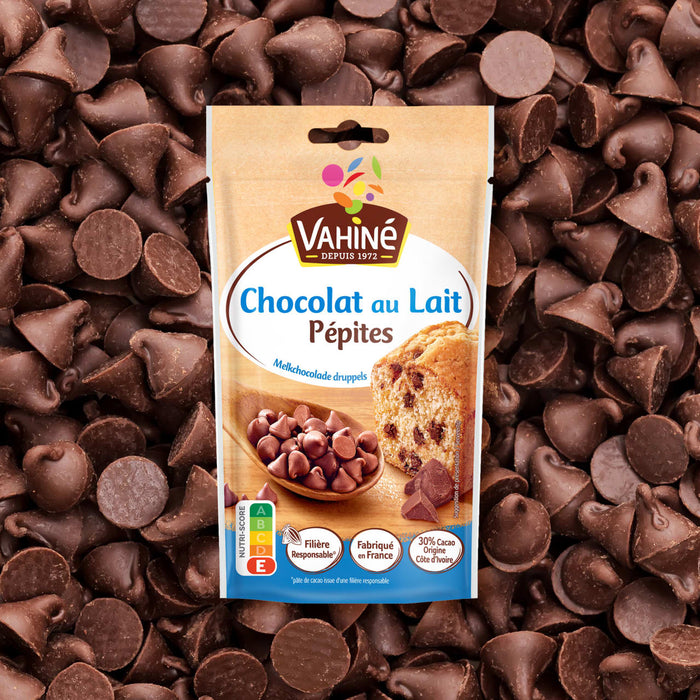 Un sachet de pépites de chocolat au lait Vahiné est présenté sur un fond de pépites de chocolat éparpillées.