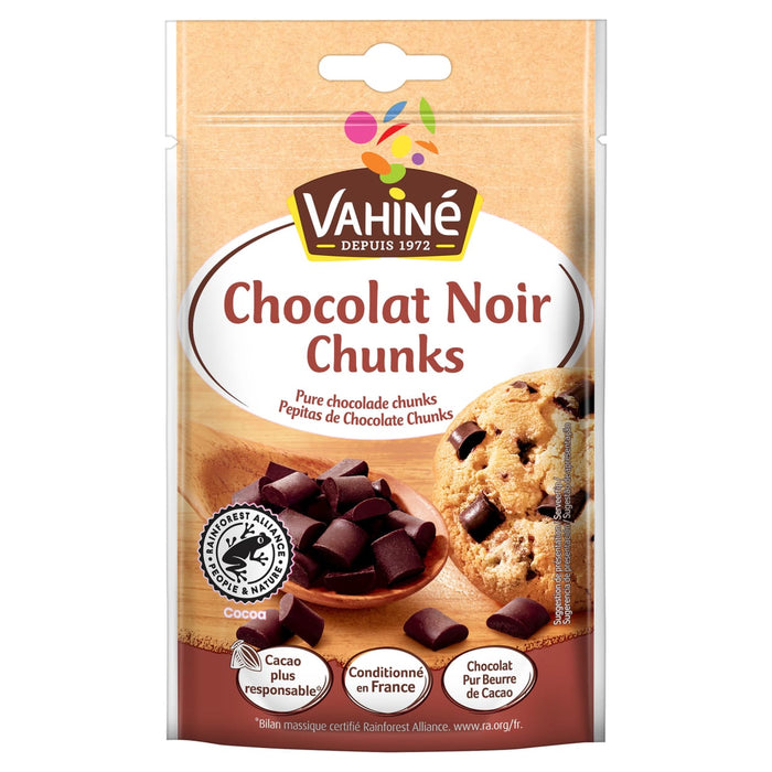 Un sachet de Vahiné Chocolat Noir Chunks avec une cuillère en bois pleine de morceaux de chocolat noir et un biscuit aux pépites de chocolat.