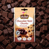 Un emballage de la marque Vahiné de Vahine Sch100G Pepites Chunkx10-Va, affichant le texte Chocolat Noir Chunks et une image de pépites de chocolat et d'un cookie, est présenté sur un fond de morceaux de chocolat noir éparpillés.