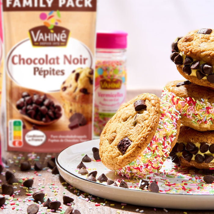 Un paquet de Vahiné Chocolat Noir Pépites est présenté à côté de sandwichs aux biscuits recouverts de pépites de chocolat et de vermicelles.