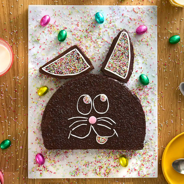 Un gâteau de Pâques fantaisiste en forme de lapin, décoré de vermicelles et d'œufs en chocolat.