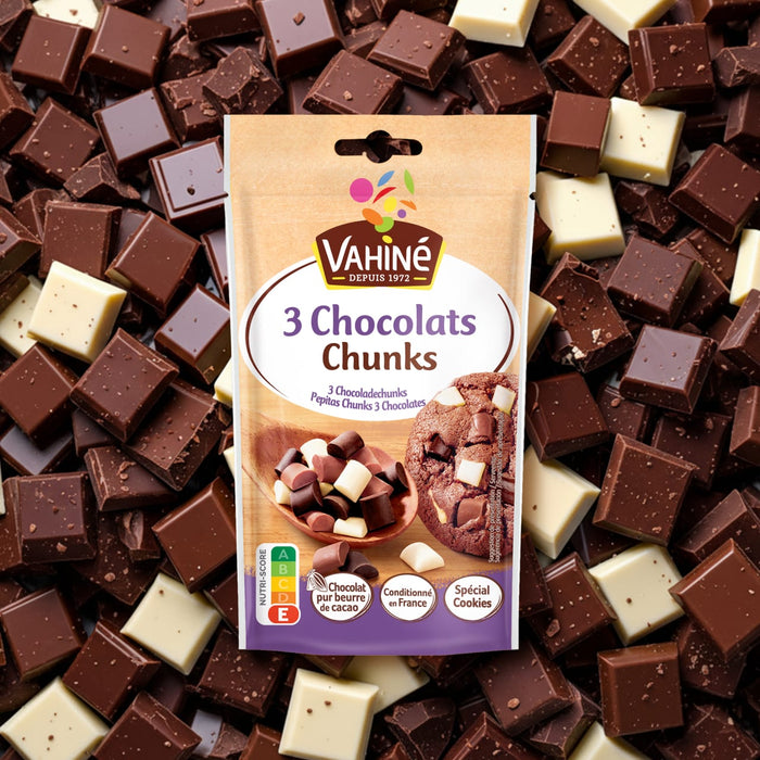 Un sachet de Vahiné 3 Chocolats Chunks est centré sur un fond de morceaux de chocolat au lait, noir et blanc éparpillés.