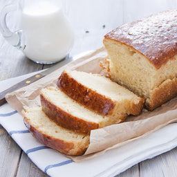 Une miche de quatre-quarts dorAC, tranchACe et servie avec un pichet de lait, suggA?re une gActerie rACconfortante et classique.