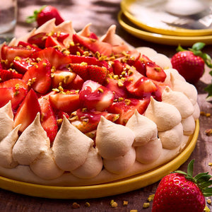 Une dAClicieuse tarte aux fraises avec une bordure de meringue et une garniture de pistaches, prACsentACe sur une assiette jaune.