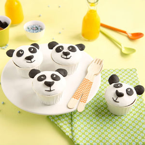 Une assiette de cupcakes sur le thA?me des pandas est posACe sur une table avec du jus et des ustensiles colorACs, parfaite pour une fAate d'enfants.