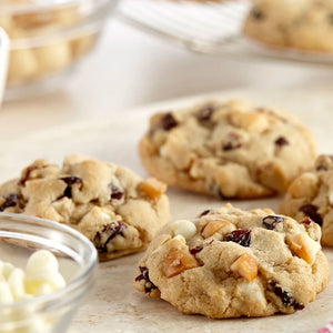 Gros plan sur des biscuits fraARchement cuits avec des pACpites de chocolat blanc, des canneberges et des morceaux de caramel.