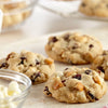 Gros plan sur des biscuits fraARchement cuits avec des pACpites de chocolat blanc, des canneberges et des morceaux de caramel.