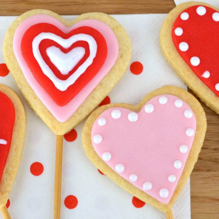 Une collection de biscuits sablACs en forme de cA?ur dACcorACs de glaA?age colorAC et certains sur des bActonnets de sucette, parfaits pour la Saint-Valentin.