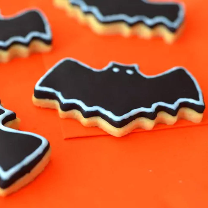 Biscuits en forme de chauve-souris dACcorACs de glaA?age noir et de contours bleu clair, parfaits pour une gActerie d'Halloween.