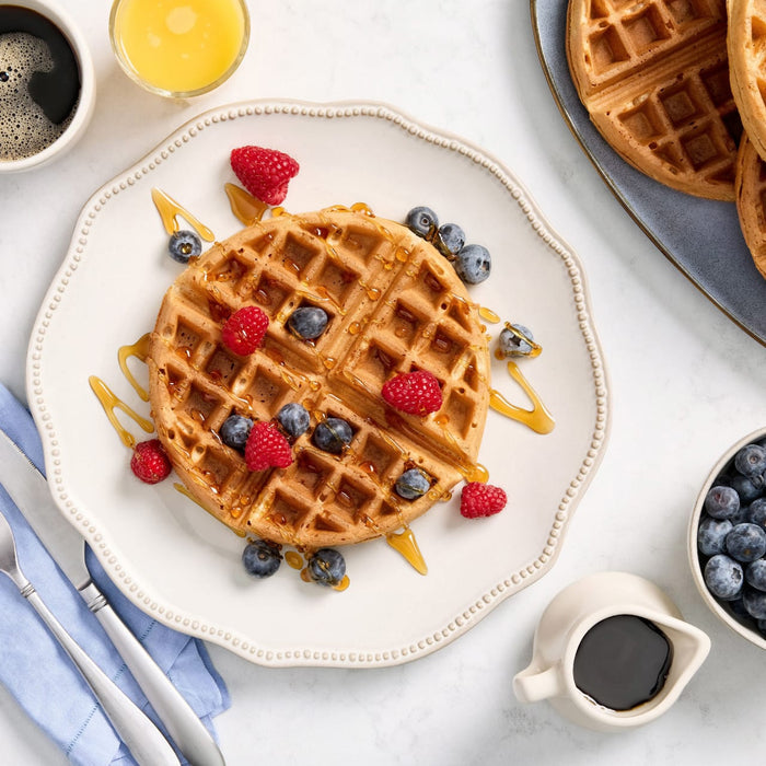 Une assiette de gaufres garnies de baies et de sirop, suggérant un délicieux petit-déjeuner ou brunch.