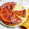 Une Galette des Rois dorée, une galette traditionnelle française, est présentée sur une assiette colorée avec une part coupée.