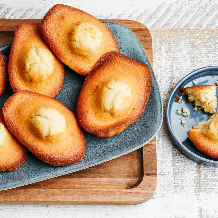 Une assiette de madeleines dorées avec une forme de coquille distinctive et une bosse caractéristique sur le dessus.