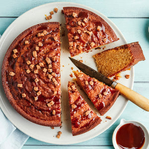 Un délicieux gâteau au caramel est tranché sur une assiette, garni de sauce au caramel et de morceaux croustillants.