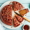 Un délicieux gâteau au caramel est tranché sur une assiette, garni de sauce au caramel et de morceaux croustillants.