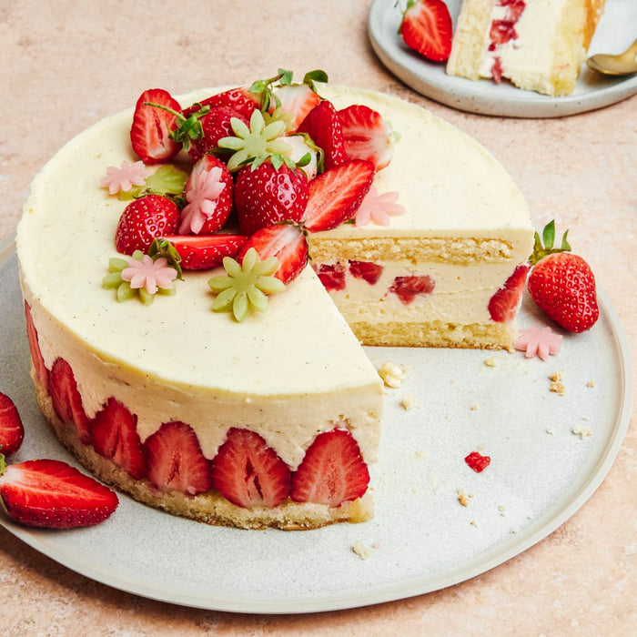 Un gâteau aux fraises visuellement attrayant avec une garniture crémeuse et des décorations de fraises fraîches.