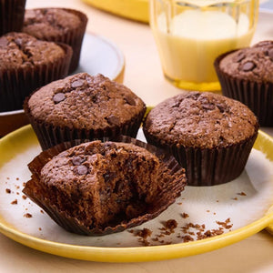 Une assiette de délicieux muffins au chocolat avec des pépites de chocolat, un muffin est partiellement déballé pour montrer sa texture.