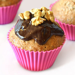 Un dAClicieux muffin dans un moule en silicone rose est garni de glaA?age au chocolat et de noix.
