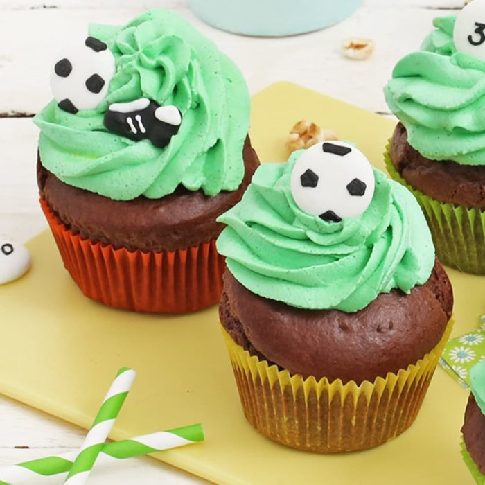 Cupcakes au chocolat décorés de glaçage vert et de décorations de ballons de soccer, parfaits pour une célébration sur le thème du sport.