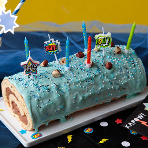 Un gâteau roulé d'anniversaire festif décoré de glaçage bleu, de vermicelles, de bougies et de décorations sur le thème des robots.