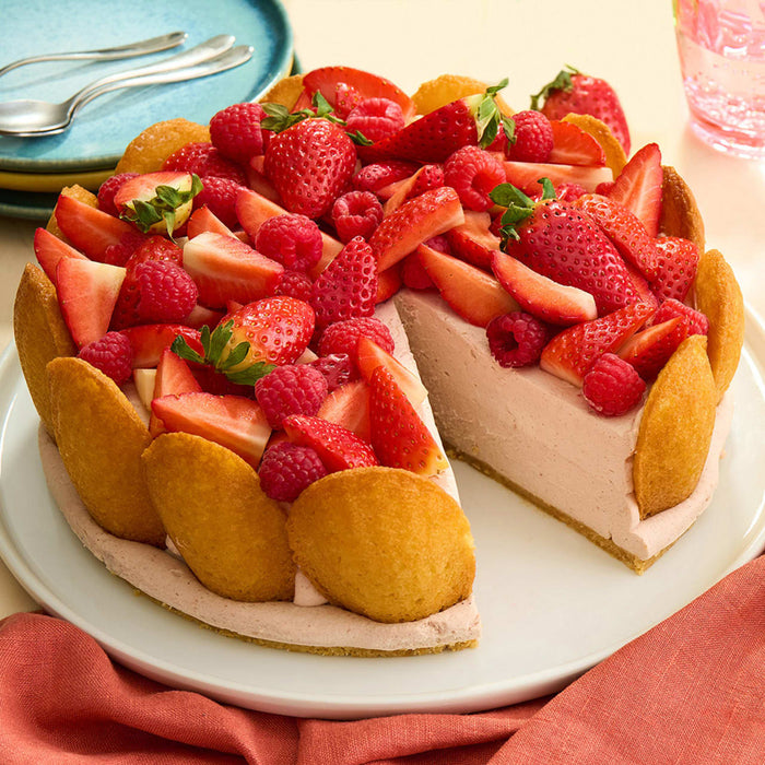 Un dAClicieux gActeau Charlotte aux fraises et aux framboises, entourAC de biscuits A? la cuillA?re, est prACsentAC sur une assiette blanche.