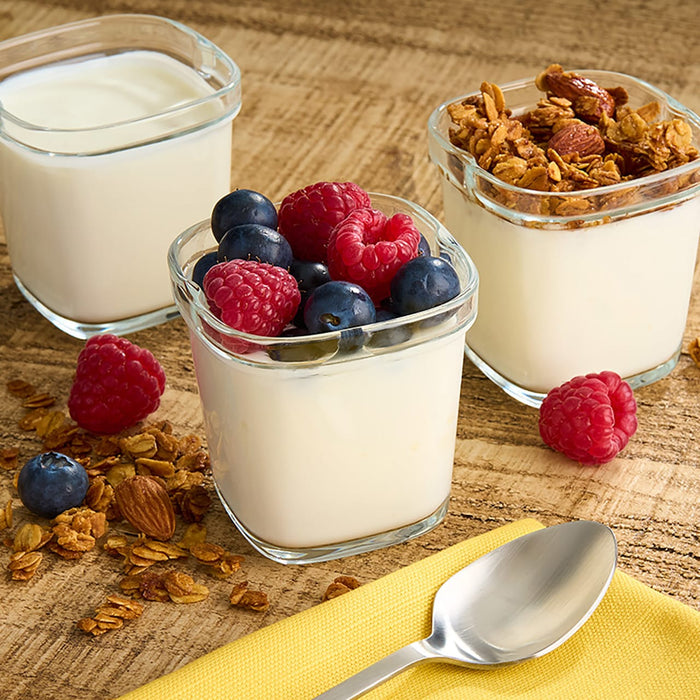 Trois petits récipients en verre remplis de yaourt, un nature, un aux baies et un au granola, présentant une option de petit-déjeuner ou de collation saine.